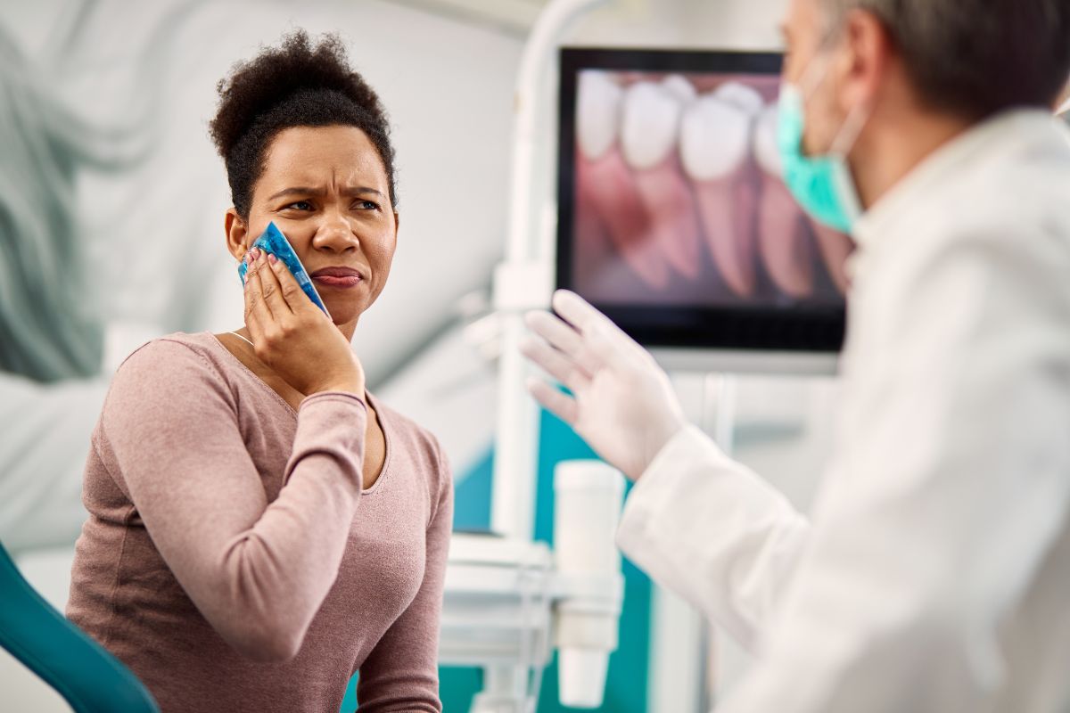 A patient consulting with a dentist while managing tooth pain emphasizes the importance of seeking professional care when dental symptoms arise.