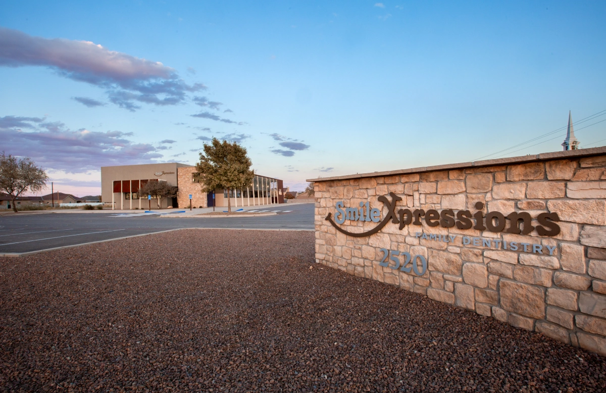 Smile Xpressions Family Dentistry stone monument sign with building in background at dusk