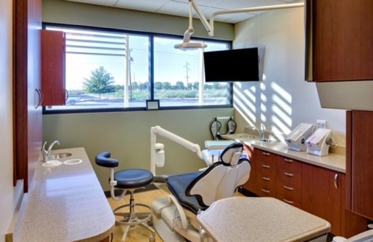 Dental treatment room with patient chair, exam light, and TV monitor