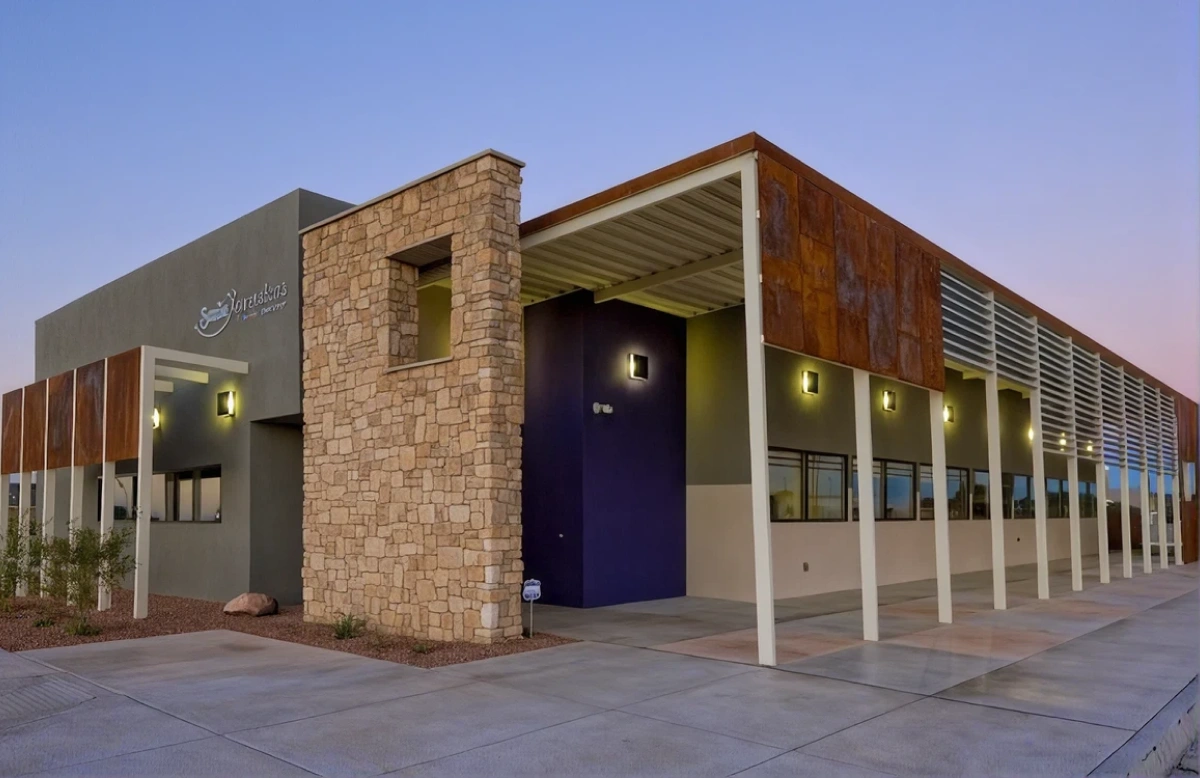 Front entrance of Smile Xpressions dental office with stone pillar and covered walkway at dusk