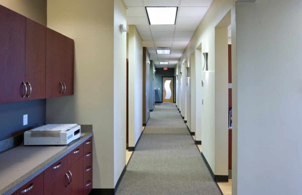 Dental office hallway lined with treatment room doors and sconce lighting