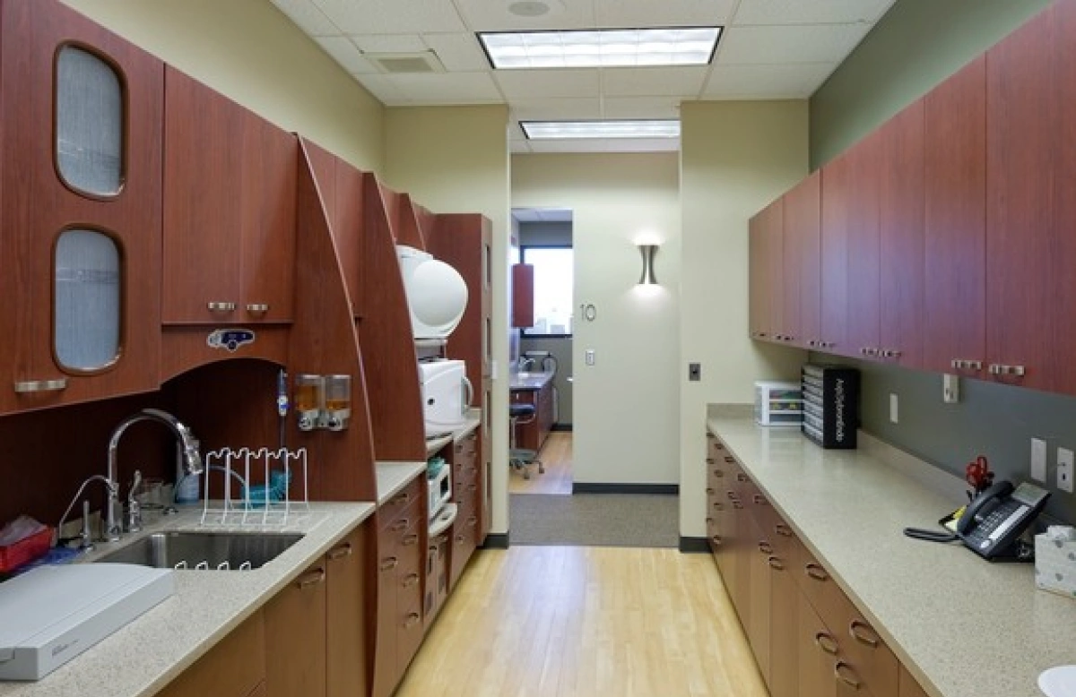 Dental office sterilization hallway with cabinets, sink, and equipment leading to treatment room