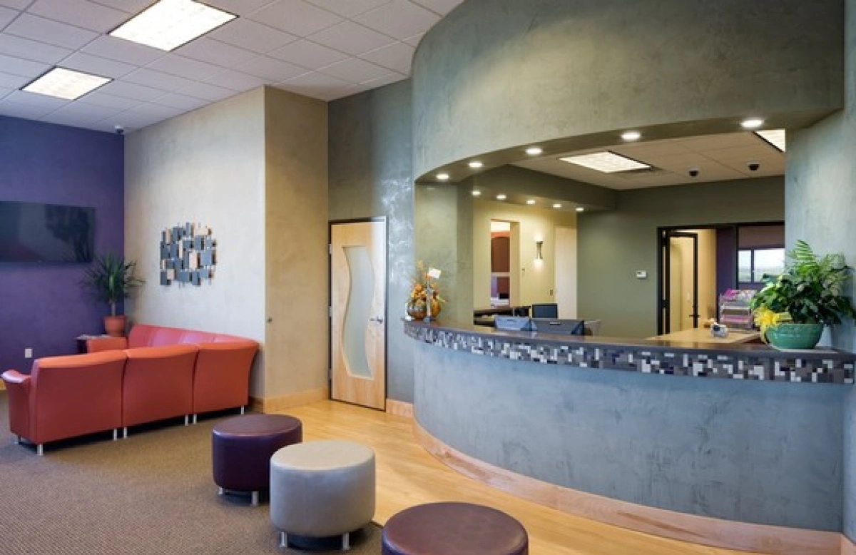 Dental office reception desk and waiting area with orange sofa and mosaic tile counter