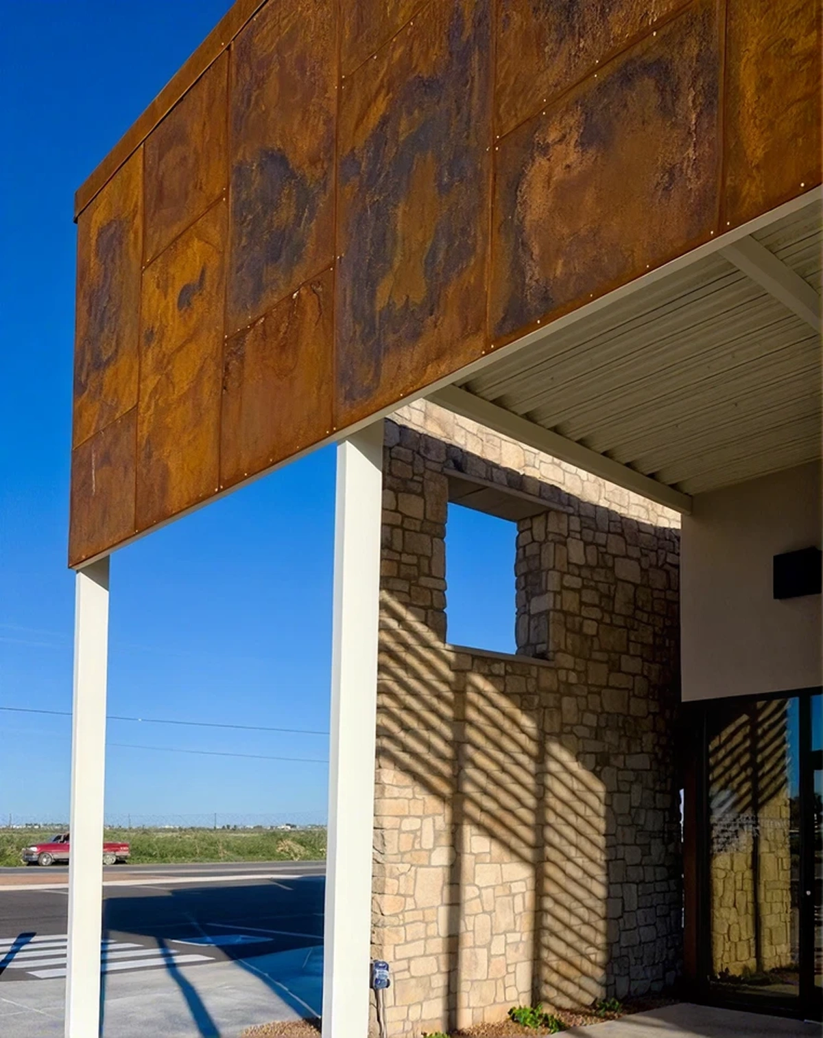 Side view of Smile Xpressions office exterior with rusted metal canopy and stone facade