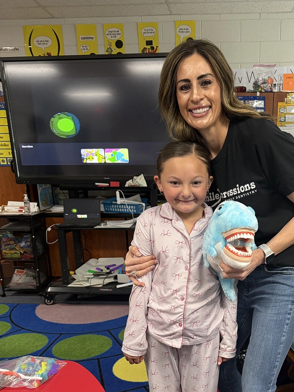 Smile Xpressions Dentistry team member with a student at a school dental event
