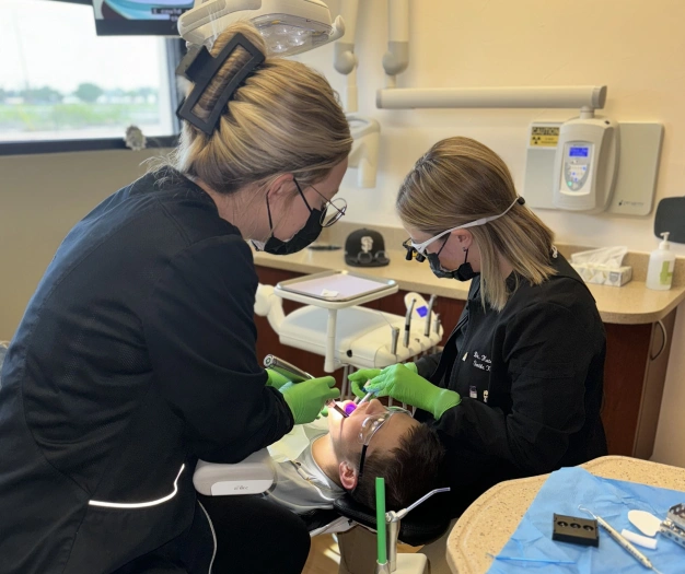 Dentist and assistant performing a tooth extraction procedure at Smile Xpressions Dentistry in Artesia, NM